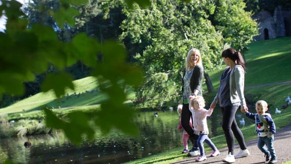 Two women and three children walking around the lake at Hardwick Park