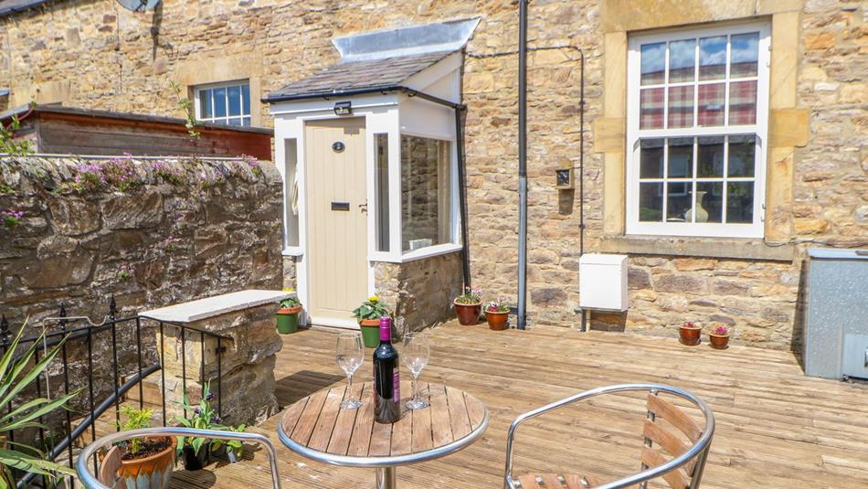 Old Workhouse image of garden patio with a small table and chairs with a bottle of wine