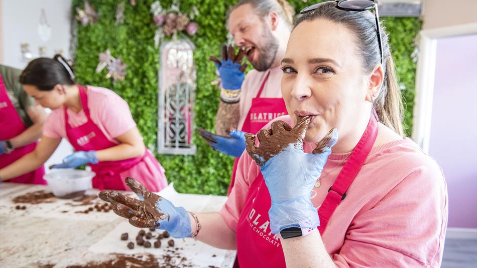 A woman is licking chocolate off her fingers, while participating in a chocolate making workshop.