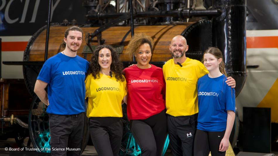 group of people in colours t shirts smiling at camera inside Locomotion museum.