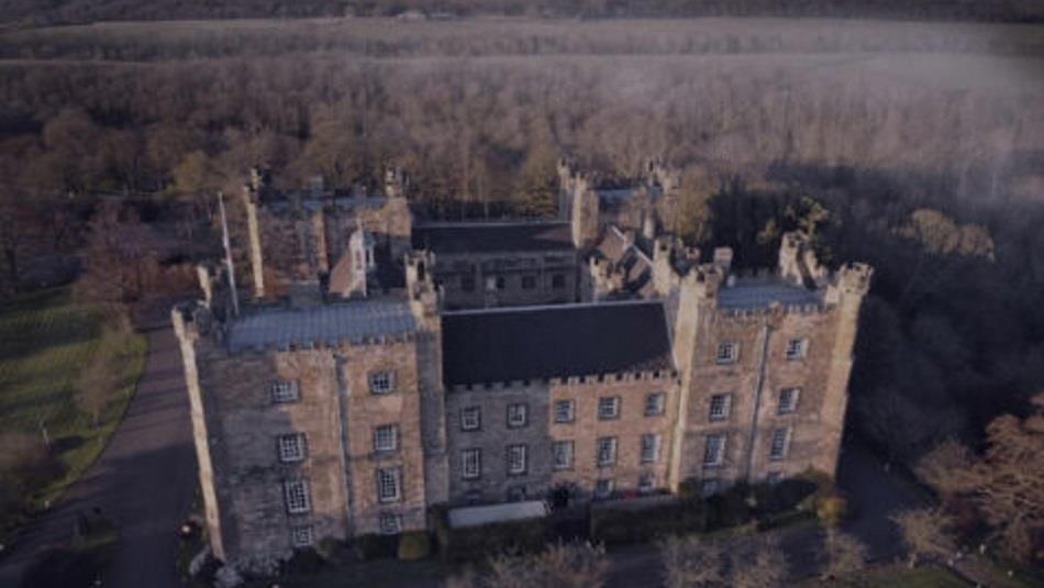 Eerie birds-eye view of Lumley Castle in fog at night.