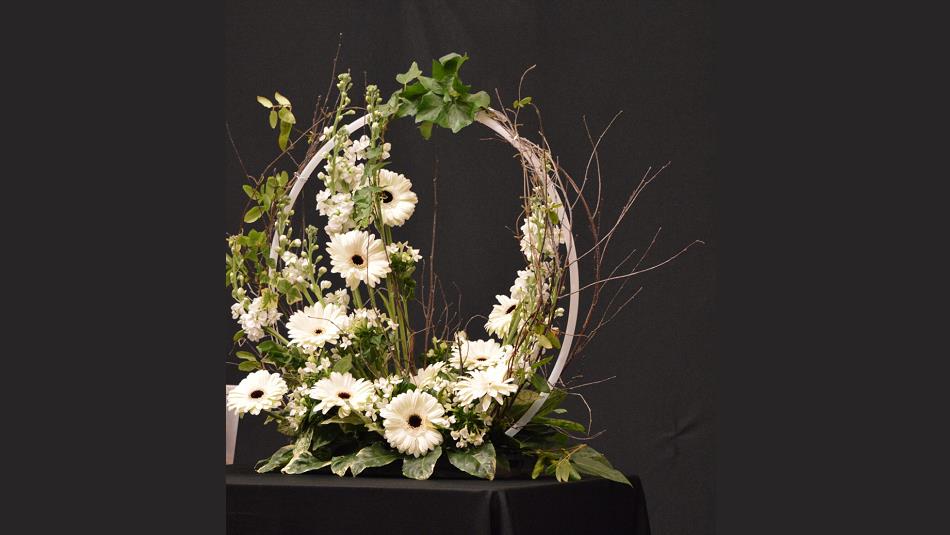 A flower arrangement in white and green formed around a circular structure