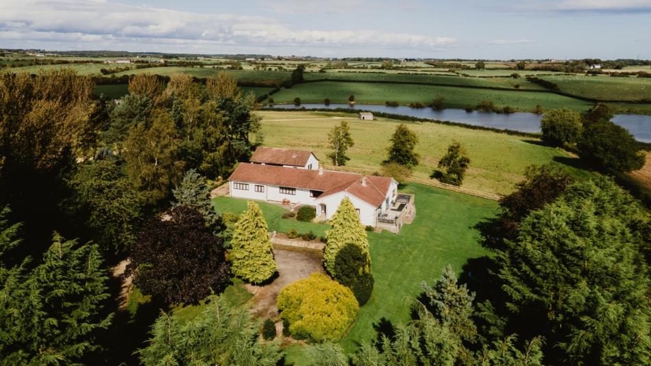 Overhead view of The Covey surrounded by tress and view of Hurworth Burn Reservoir.