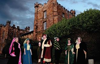 Men and women dressed in Elizabethan costume with Lumley Castle in the background