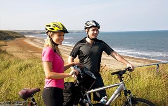 Two people on bikes at the coast