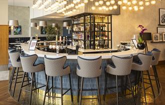Jozef’s Riverside Bar & Restaurant - seating around a stylish bar with soft lighting above.