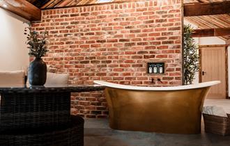 High ceilings, wood panelling, bespoke candle chandeliers and a large free-standing bath against the exposed brick wall.