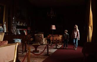 Two children walking in a dark room at Raby Castle