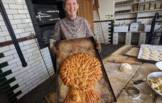 Baker making a large, decorative loaf of bread at Beamish Museum
