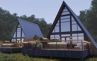 Exterior View of Treehouses set in woodland with full height windows which allow natural light to flood in and wrap around balcony with sunken hot tub