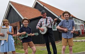 A Skiffle group of two adults and two children in front of Beamish Museum's 1950s welfare hall.