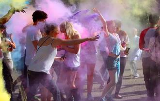 Crowd laughing and covered in colourful powder