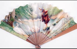 A historical fan with an image of a milkmaid displayed on a white background