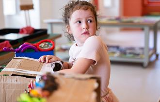 A child at The Bowes Museum opening a box.