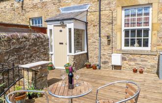 Old Workhouse image of garden patio with a small table and chairs with a bottle of wine