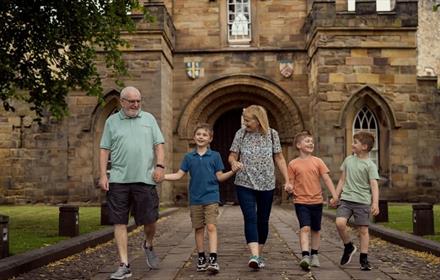 A family walking in front of the gateway of Durham Castle