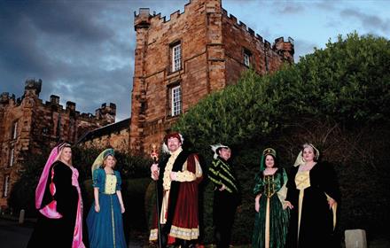 Men and women dressed in Elizabethan costume with Lumley Castle in the background