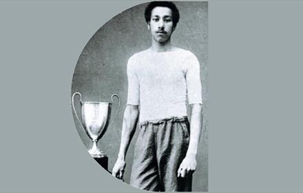 Arthur Wharton standing beside a football trophy