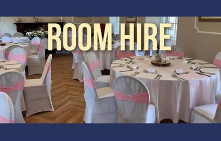 Dining room set up with round tables.  White table and chairs coverings - chairs with a pink sash.