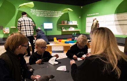 Children and an adult sitting around a table crafting with paper