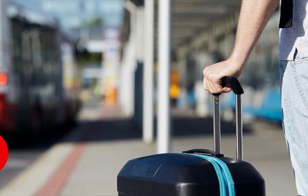 A person holding a suitcase in a bus station