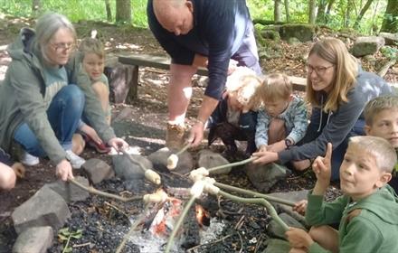 Adults and children sitting around a campfire toasting Marshmallows