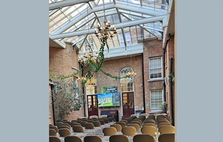 Glass ceiling room with chairs set out in Theatre style, screen