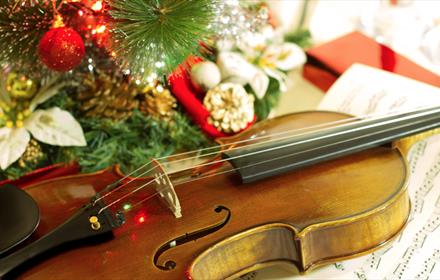 A violin and sheet music with Christmas decorations