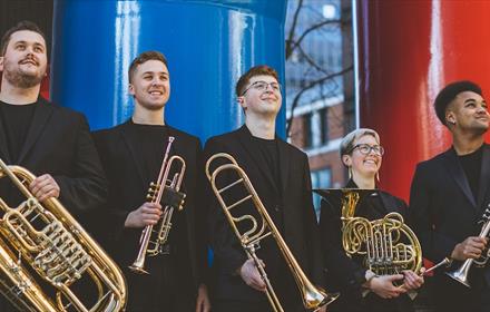 Five musicians dressed in black with brass instrument.