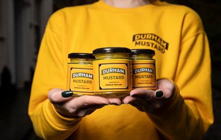 Holding 3 jars of Durham mustard in hands