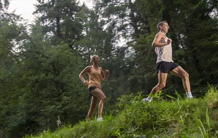 Two people running through a forest