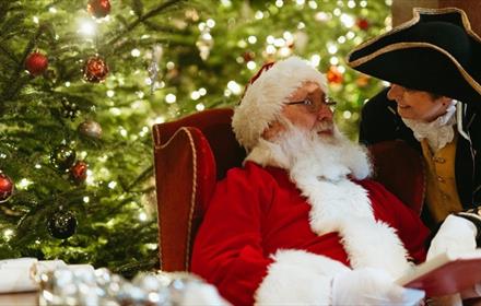 Father Christmas sitting in front of a Christmas Tree at Raby Castle