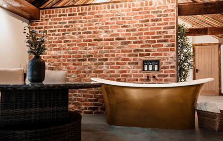High ceilings, wood panelling, bespoke candle chandeliers and a large free-standing bath against the exposed brick wall.