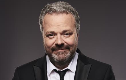 Headshot of Hal Cruttenden wearing a suit and smiling.