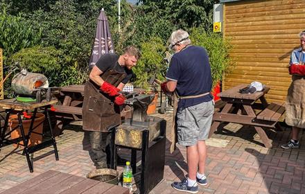 Blacksmith Workshops at South Causey Inn. People enjoying the workshop on a sunny day.