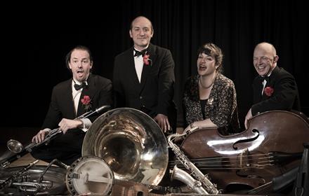 Thomas Spats Langham and his band Hot Fingers. A group of four people standing with musical instruments to the foreground