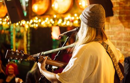 A musician playing guitar and singing to an audience at Katie O'Brien's.