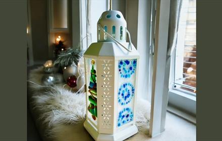 A white lantern with a fused glass design on glass panels