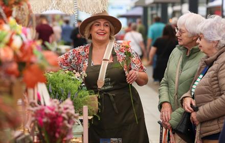 People visiting a colourful flower stall at the Artisan Market at Dalton Park Outlet and Outdoors.