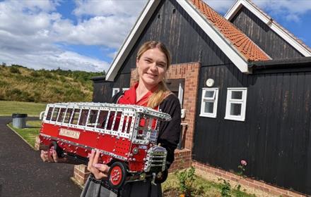 Image of a woman holding a bus made from Meccano.