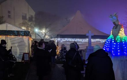Image of people enjoying Christmas stalls in the evening.