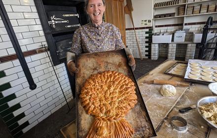 Baker making a large, decorative loaf of bread at Beamish Museum
