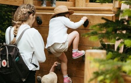 Child playing at the Plotters Forest with an adult at Raby Castle