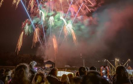 Crowds of people watching a firework display.