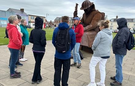 Group of people beside 'Tommy' statue, taking part in guided walk in Seaham