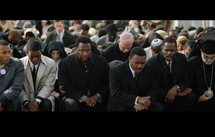 a crowd of people with their heads bowed, praying