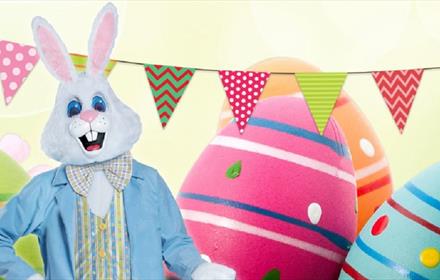 Image of the Easter Bunny in front of Easter Eggs and bunting.
