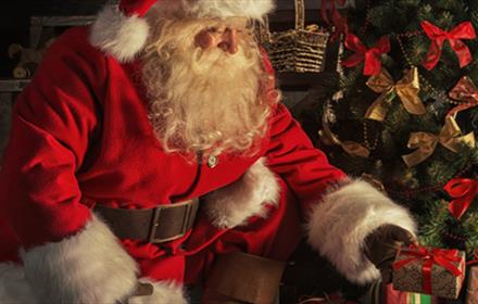Santa placing presents under the tree.