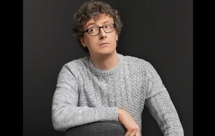 Luke Connell resting his arm on a chair and glancing sideways.