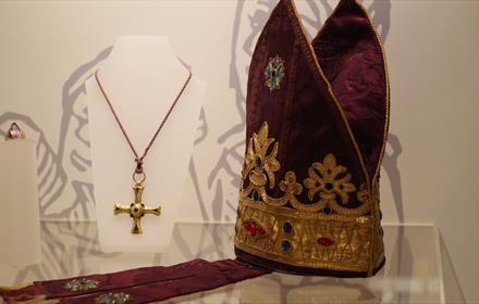 Symbol of the cross on a necklace and a priest's headwear.